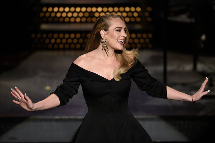 Adele smiling on stage while hosting Saturday Night Live