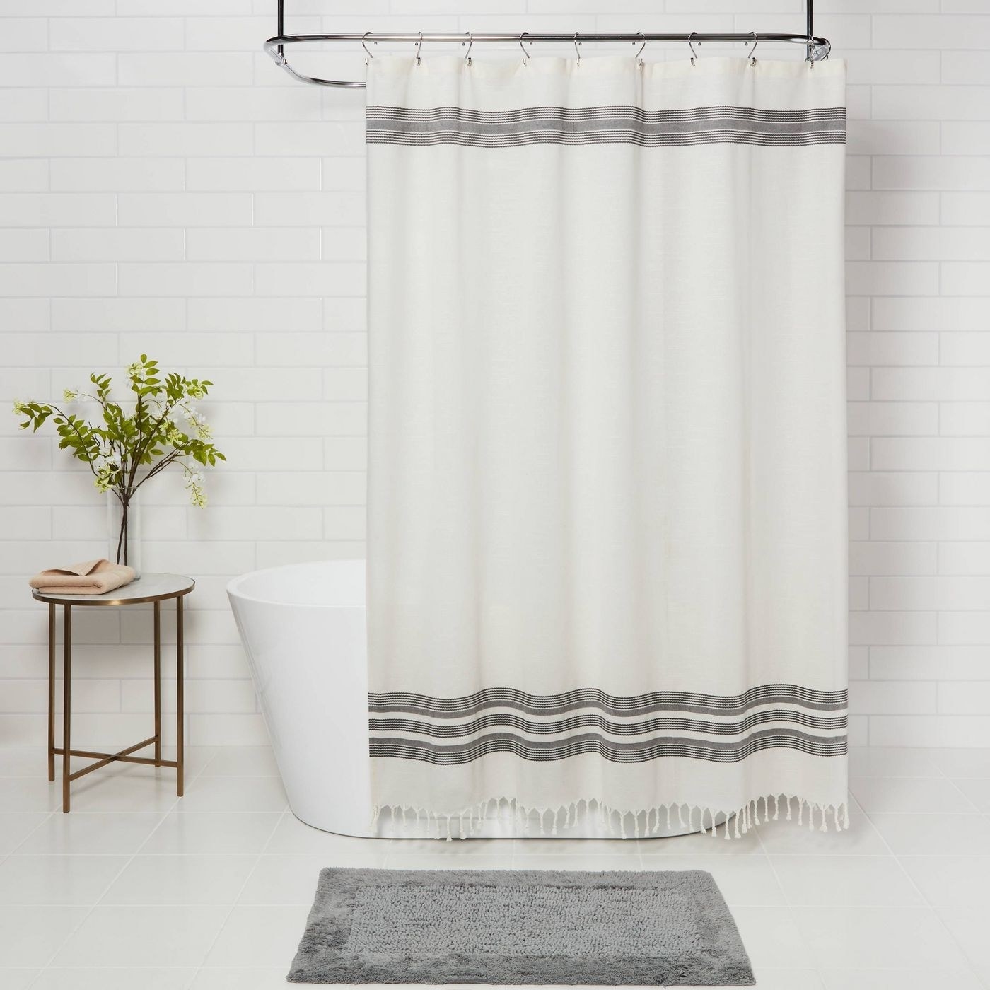 white shower curtain with gray stripes and fringe at the bottom