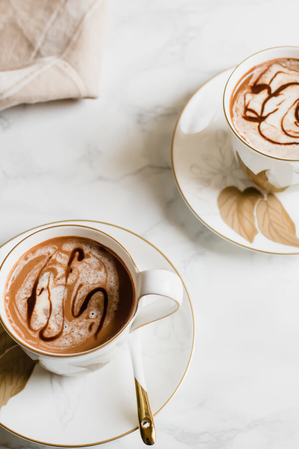 Two cups of hot chocolate, which contain tahini and cardamom
