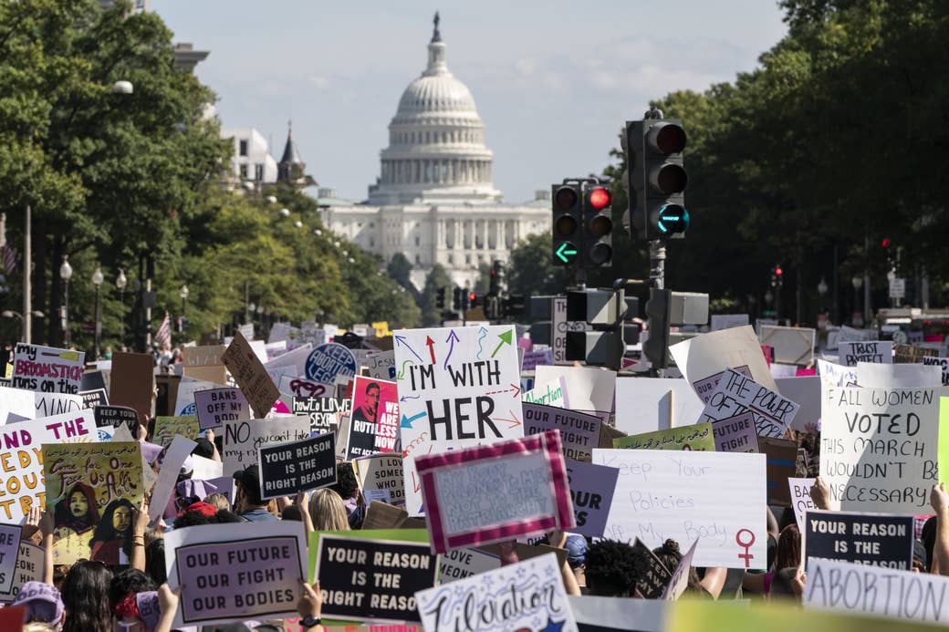 Protesters holding up many signs, such as &quot;Our Future Our Fight Our Bodies,&quot; with the US Capitol in the background