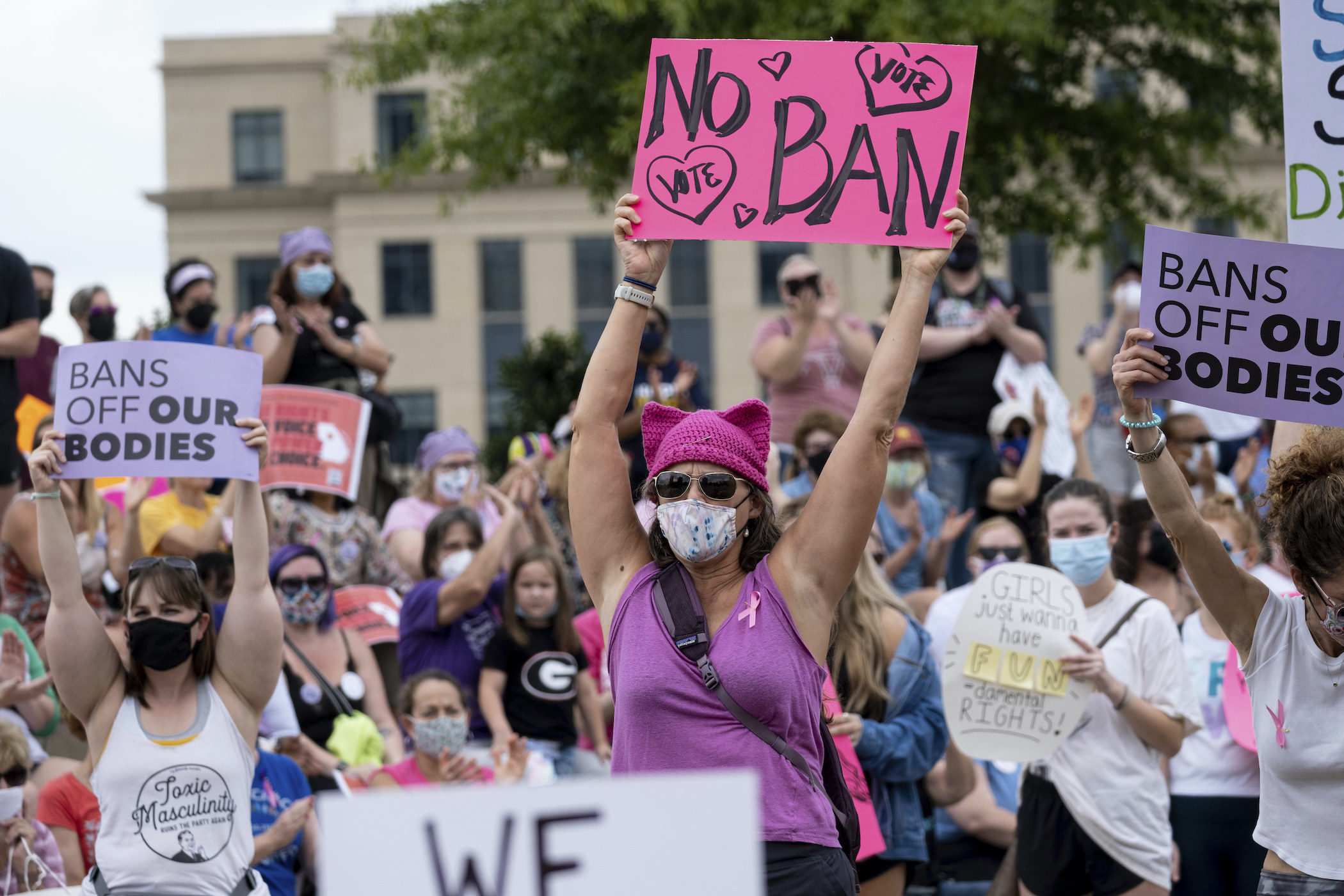 Protesters wearing masks and some holding signs, including &quot;Bans Off Our Bodies&quot; 