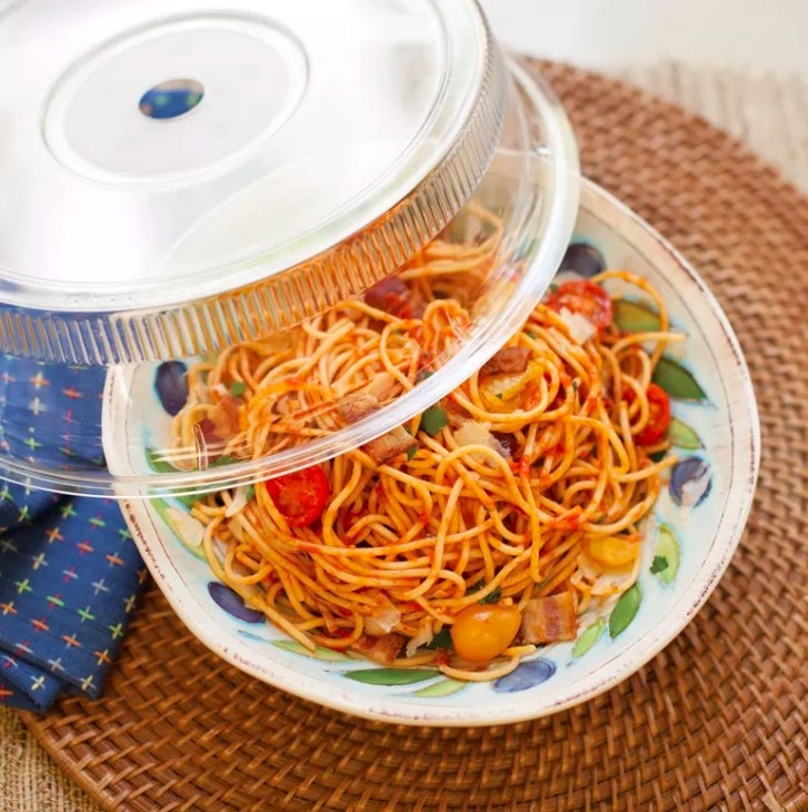 The clear plate cover being placed over a dish of spaghetti