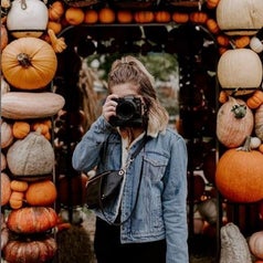 a reviewer posing in the blue demin jacket in front of pumpkins