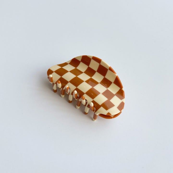 The same hair clip laying flat, showing six closures on each side and a curved edge/handle for easy holding