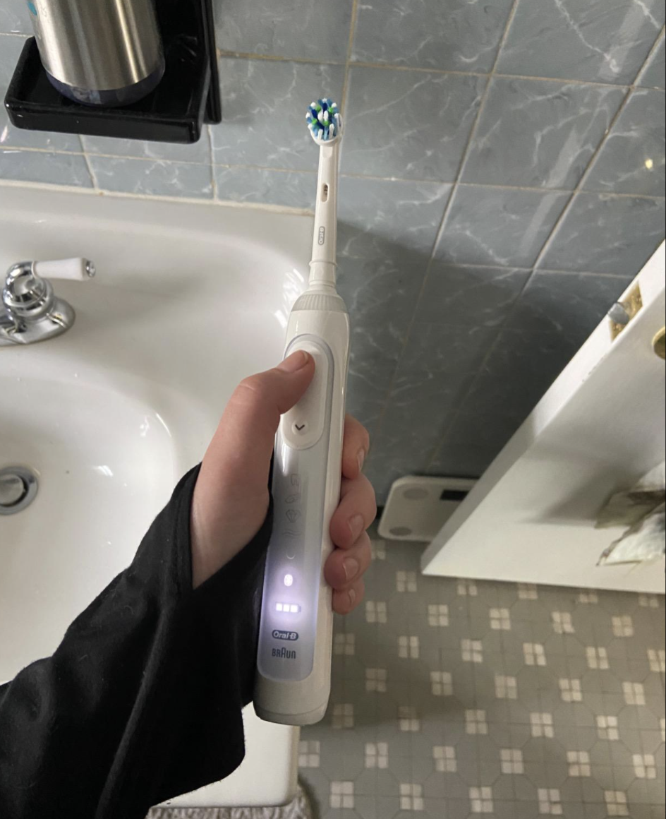Reviewer holding a white toothbrush with settings lit up on handle