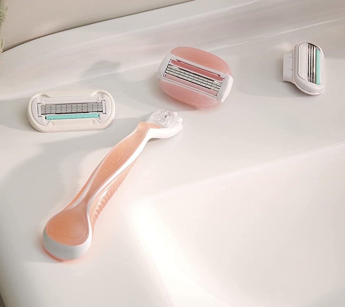 A pink razor handle next to three razor heads