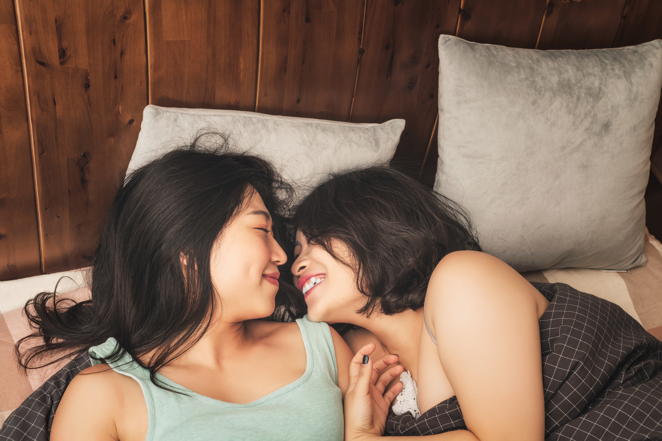 Two women kissing in bed