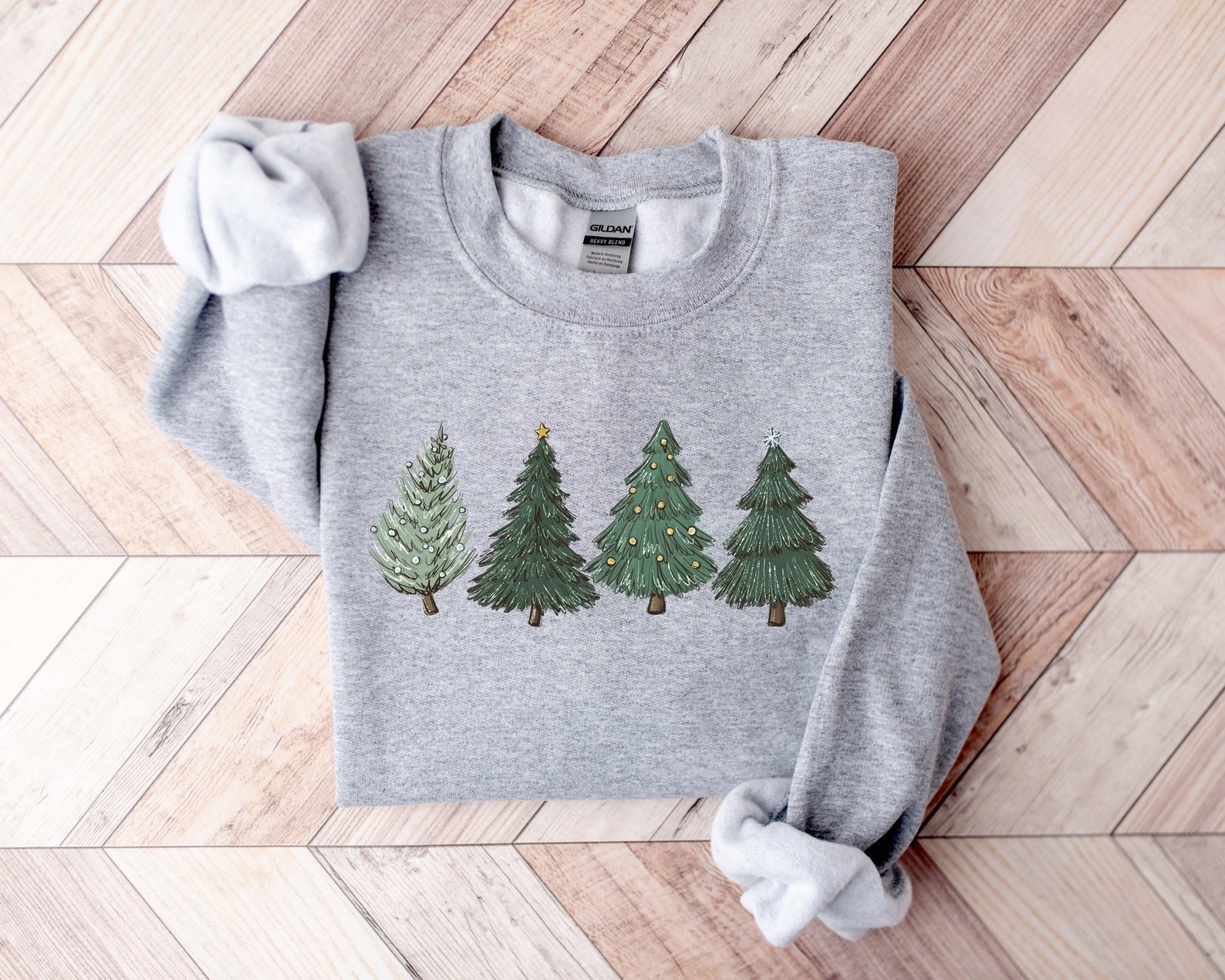 a grey sweatshirt with four different christmas trees on it