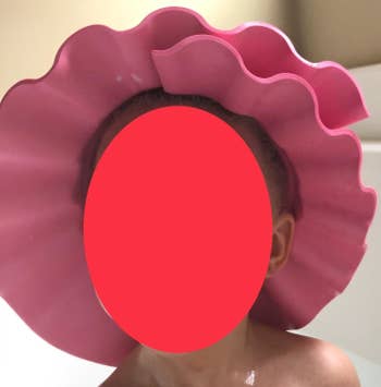 reviewer's child wearing a pink shower visor
