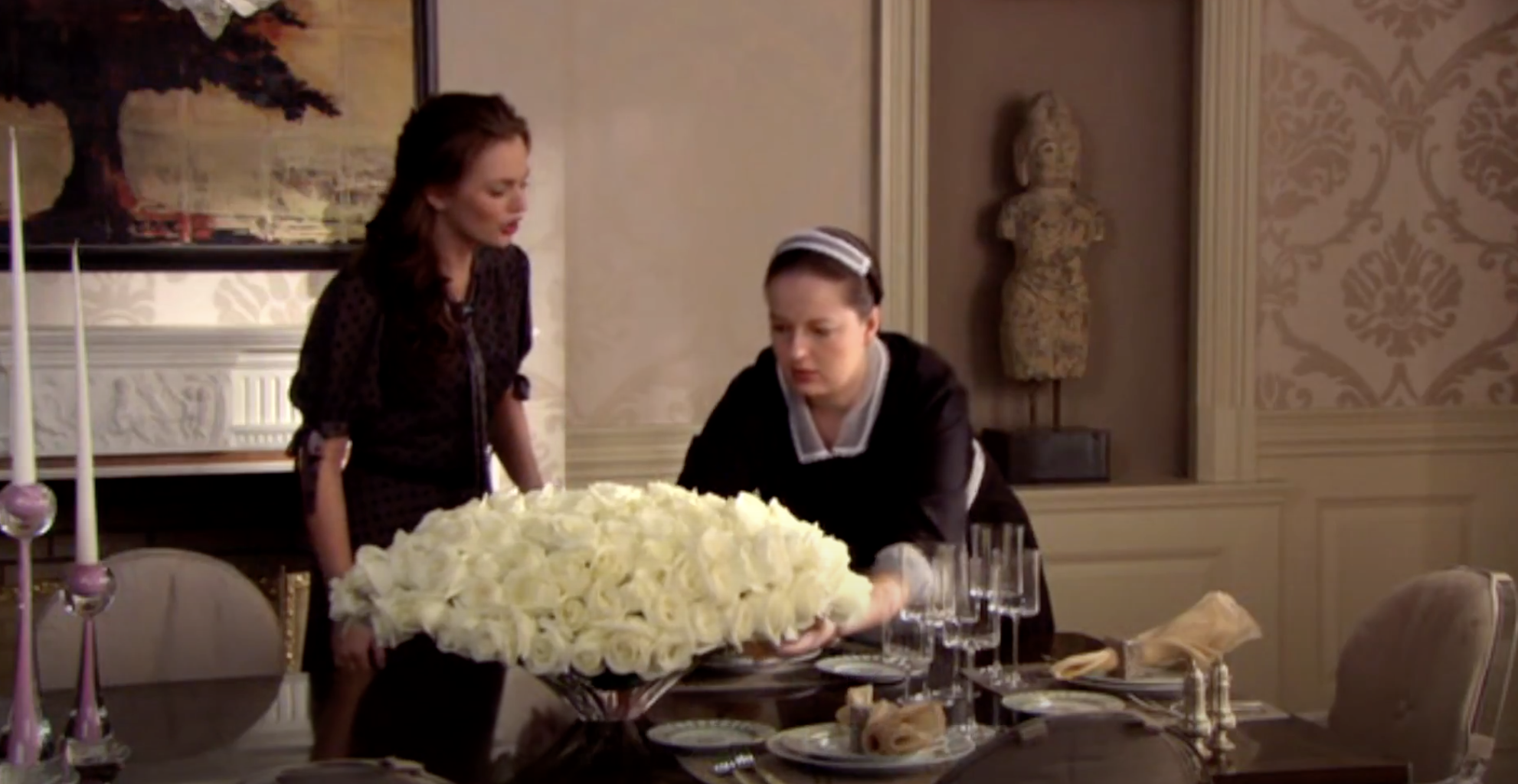 a maid rearranging flowers while the teenager stands nearby talking