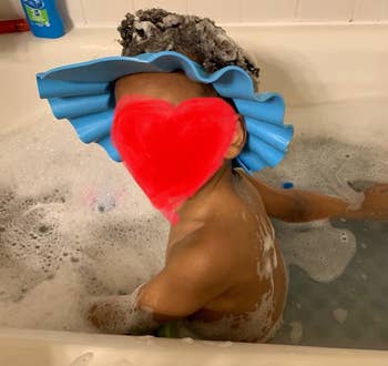 Reviewer's child wearing the blue hat in the bath