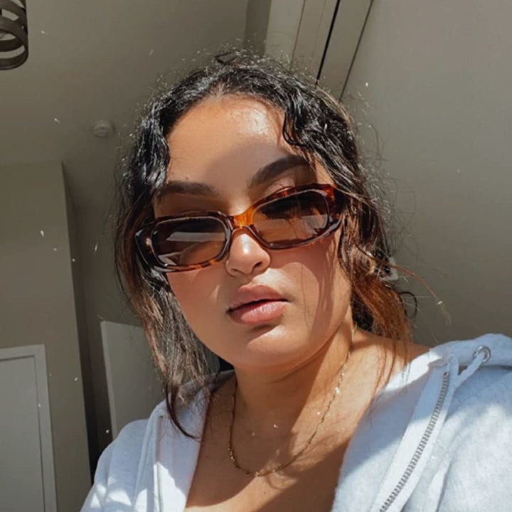 A reviewer wearing the sunglasses with the leopard frame and brown lenses