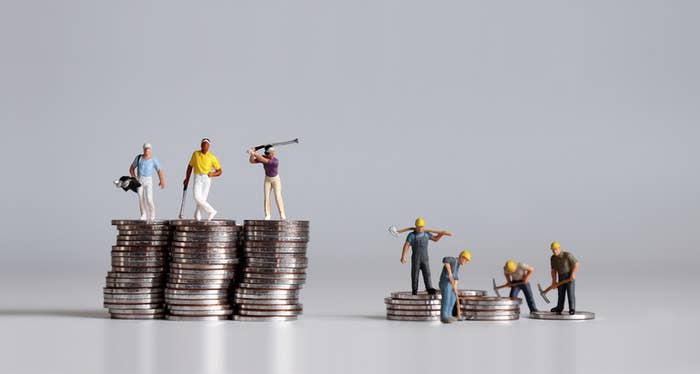 Figures of men playing golf on a large pile of coins while figurines of blue collar workers are on a small pile of coins