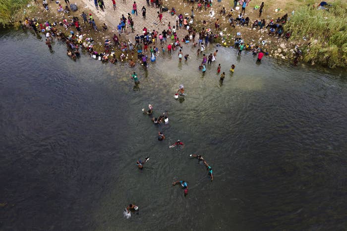 An aerial view of people wading through a river near shore