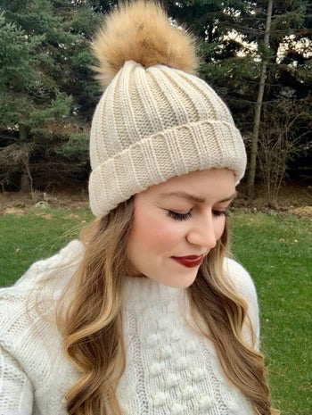 a reviewer in a white hat with a tan pom pom