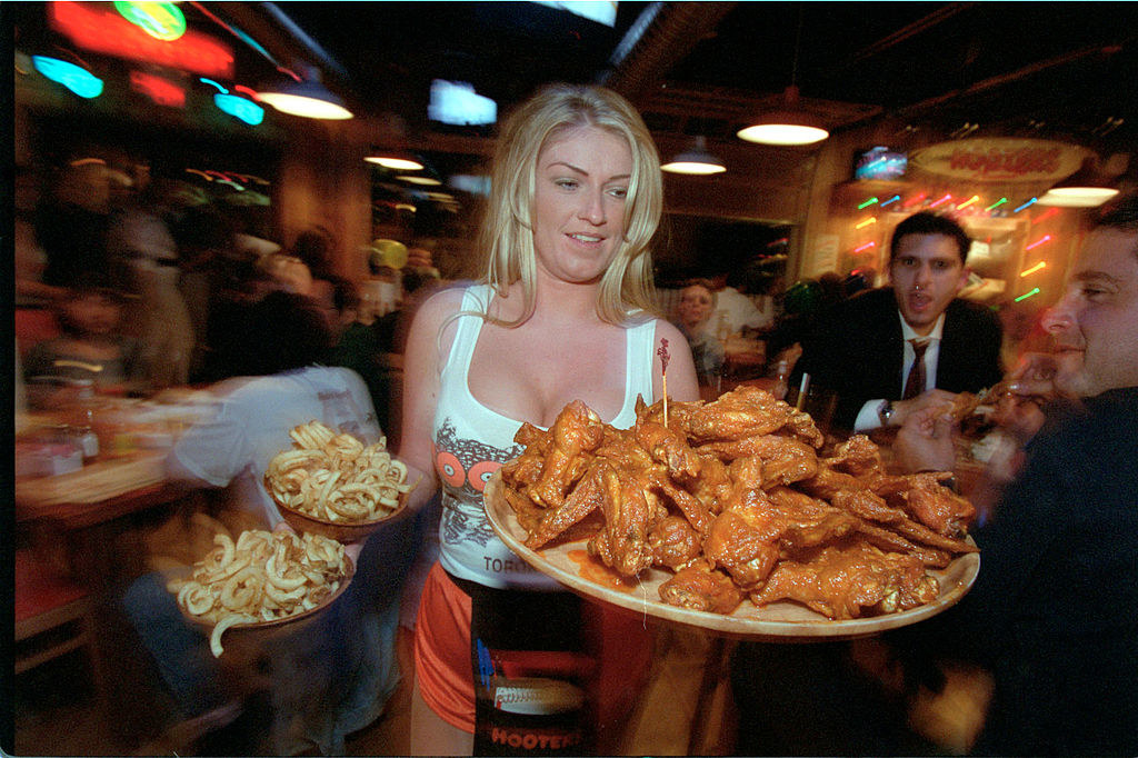 Hooters waitress serves chicken wings and french fries