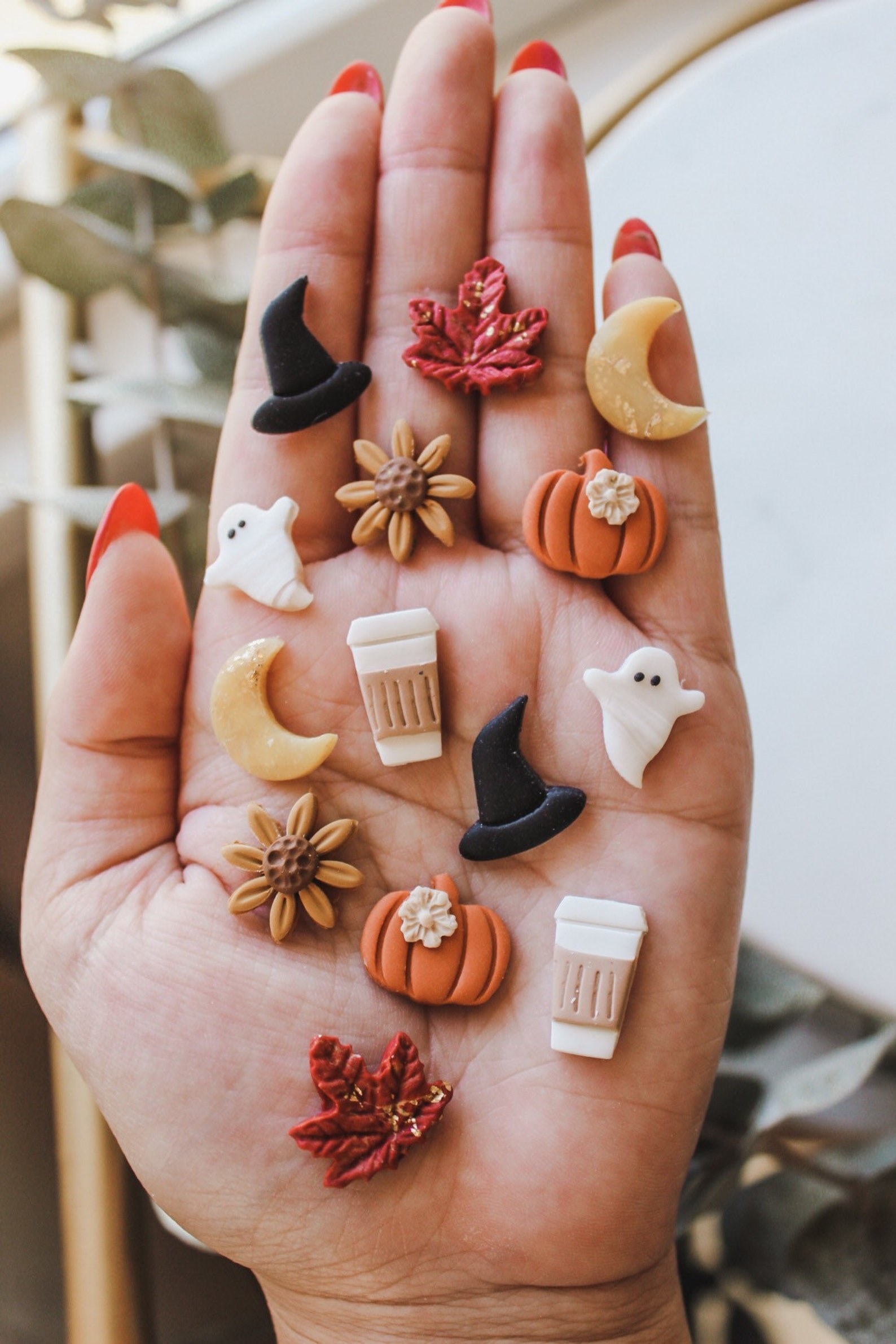 fall-themed clay studs assorted held in a hand