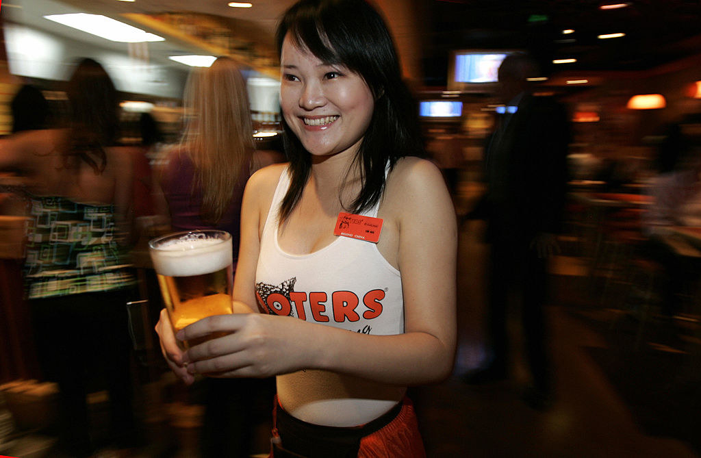 A waitress at Hooters serves beer