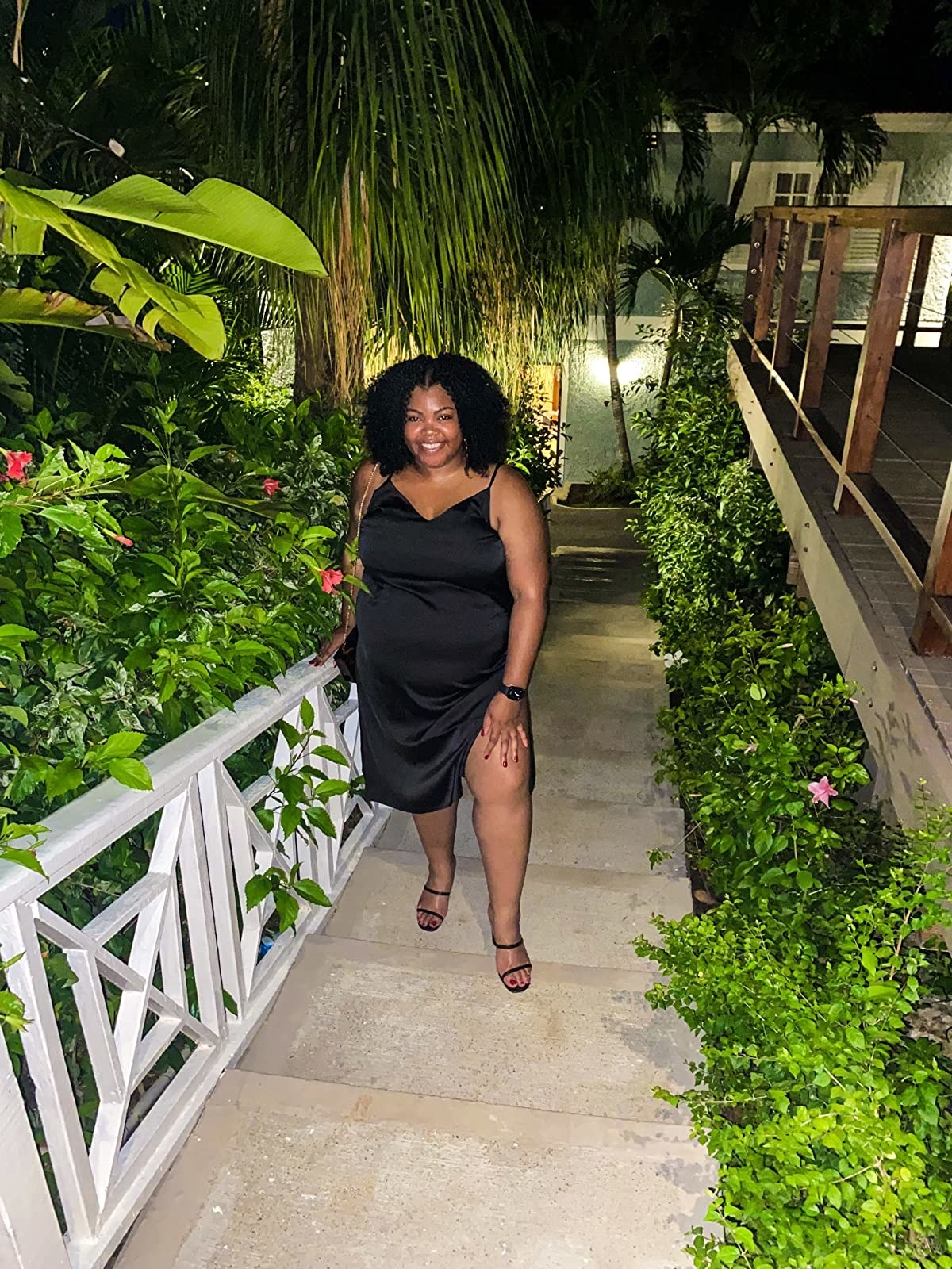 A reviewer posing in the black dress outside, showing the slit on the left side goes up to mid-thigh.