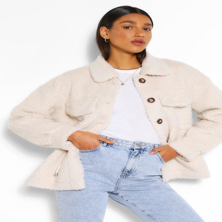 A model wearing the teddy shacket in cream and showing the two big pockets on the chest