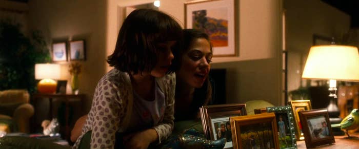 Babysitter Jessica and the daughter near family photos, one of which has Emma Stone&#x27;s character in it