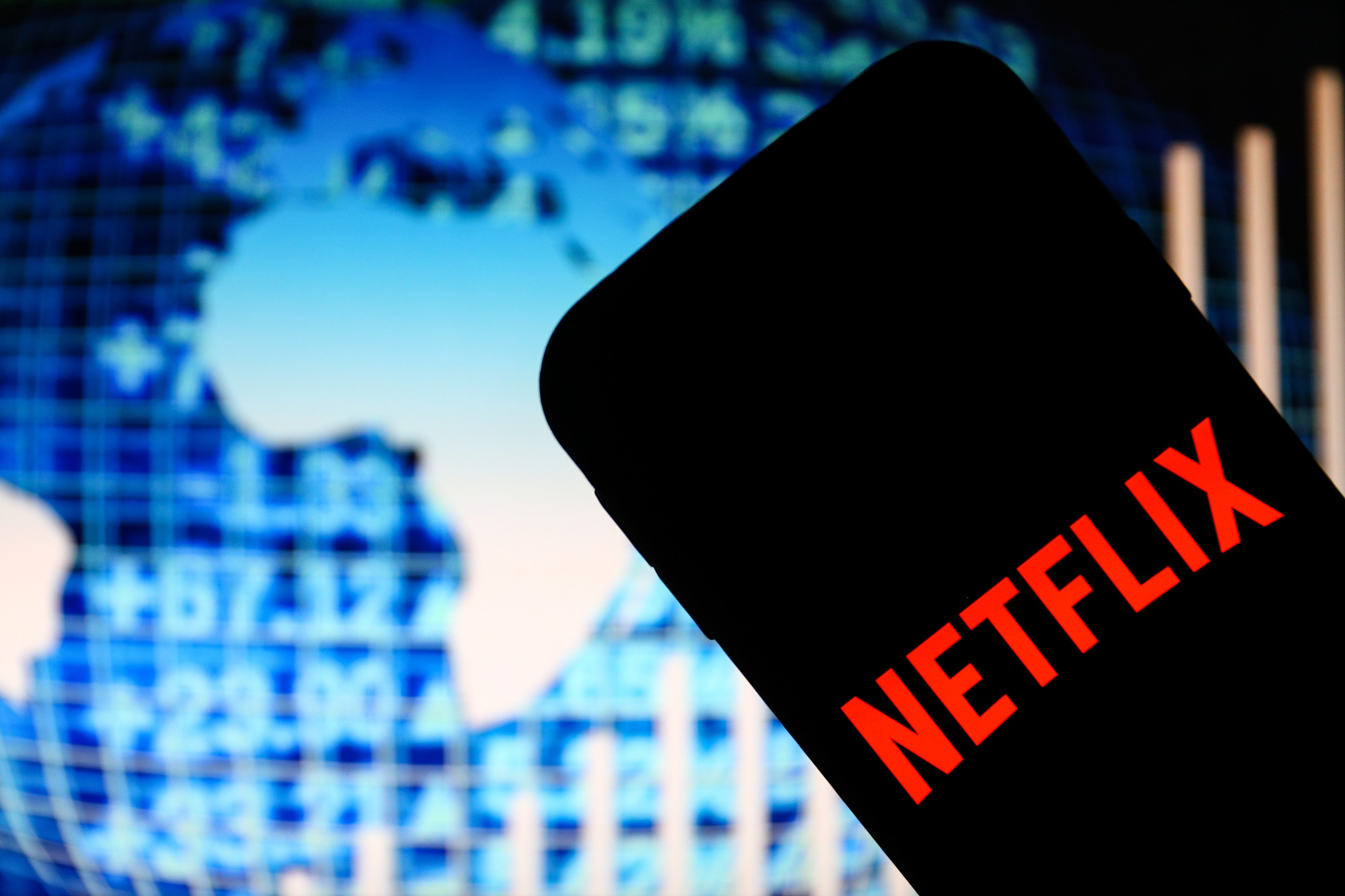 The Netflix logo is displayed on a smartphone with blue world data stats in the background