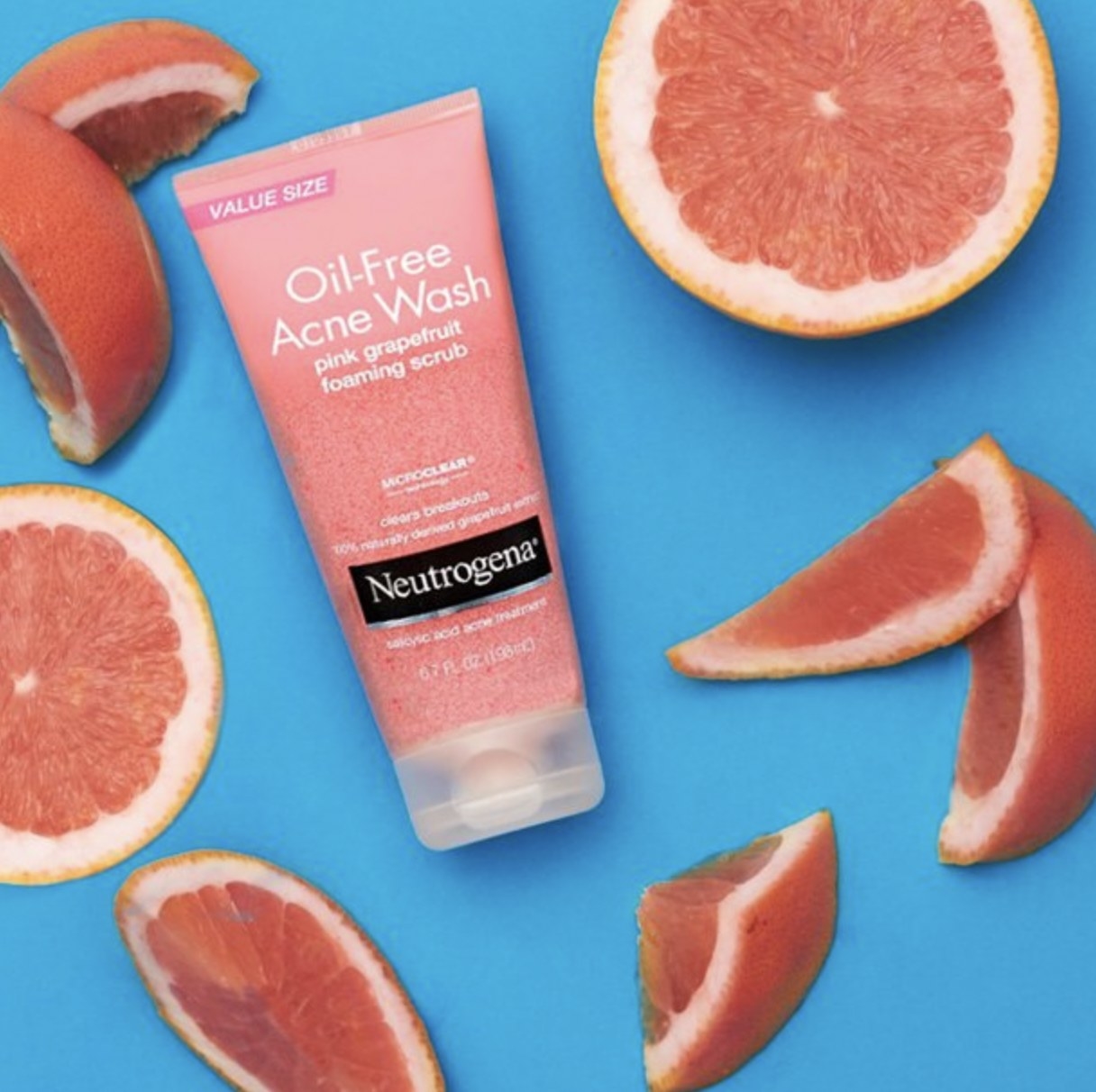 A bottle of face scrub with cut grapefruit