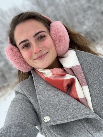 a reviewer in pink fuzzy earmuffs