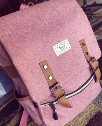 reviewer's pink backpack with an envelope-like from closure with two brown faux leather snaps