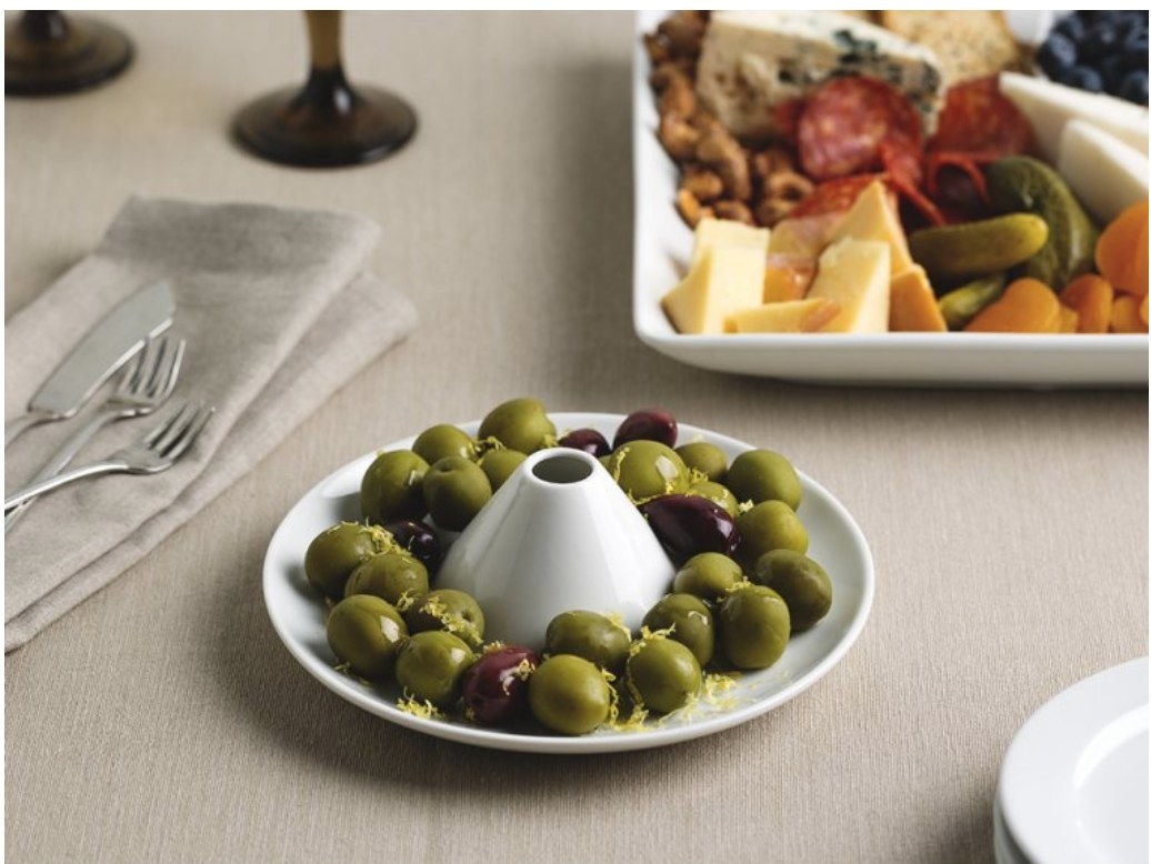 An olive boat with olives on a table.
