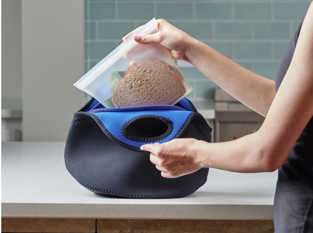 Model putting sandwich bag into blue lunch bag