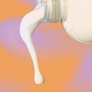 A bottle pouring out some of the milky toning lotion