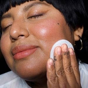A model applying the milky toning lotion to their face