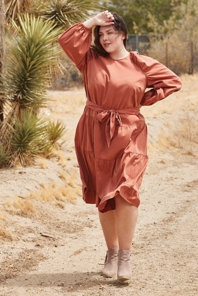 a model wearing the dress in a rust color with beige booties