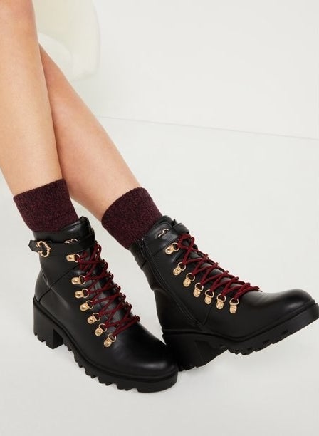 a person wearing the boots in black with burgundy laces and gold hardware