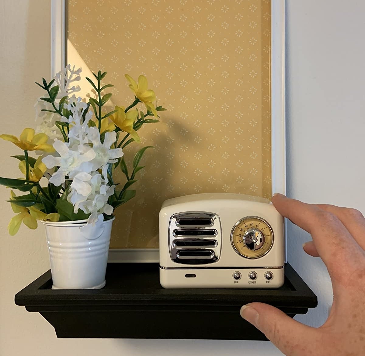 image of reviewer placing ivory speaker on a floating shelf