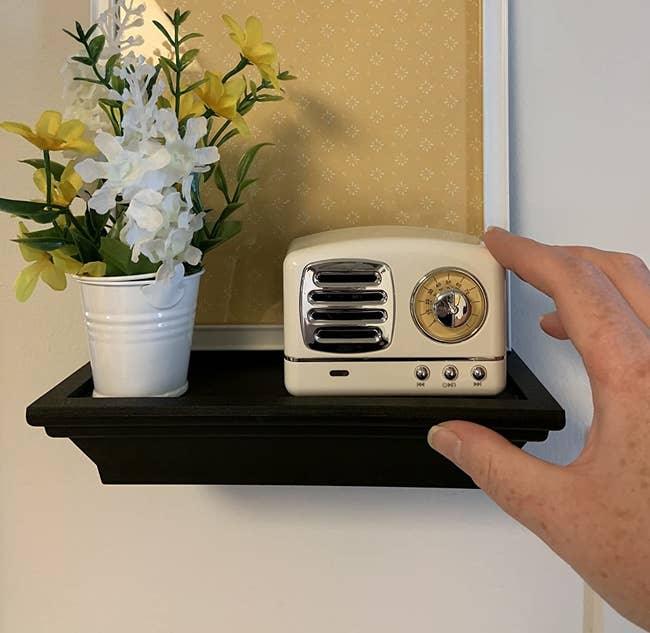 image of reviewer placing ivory speaker on a floating shelf