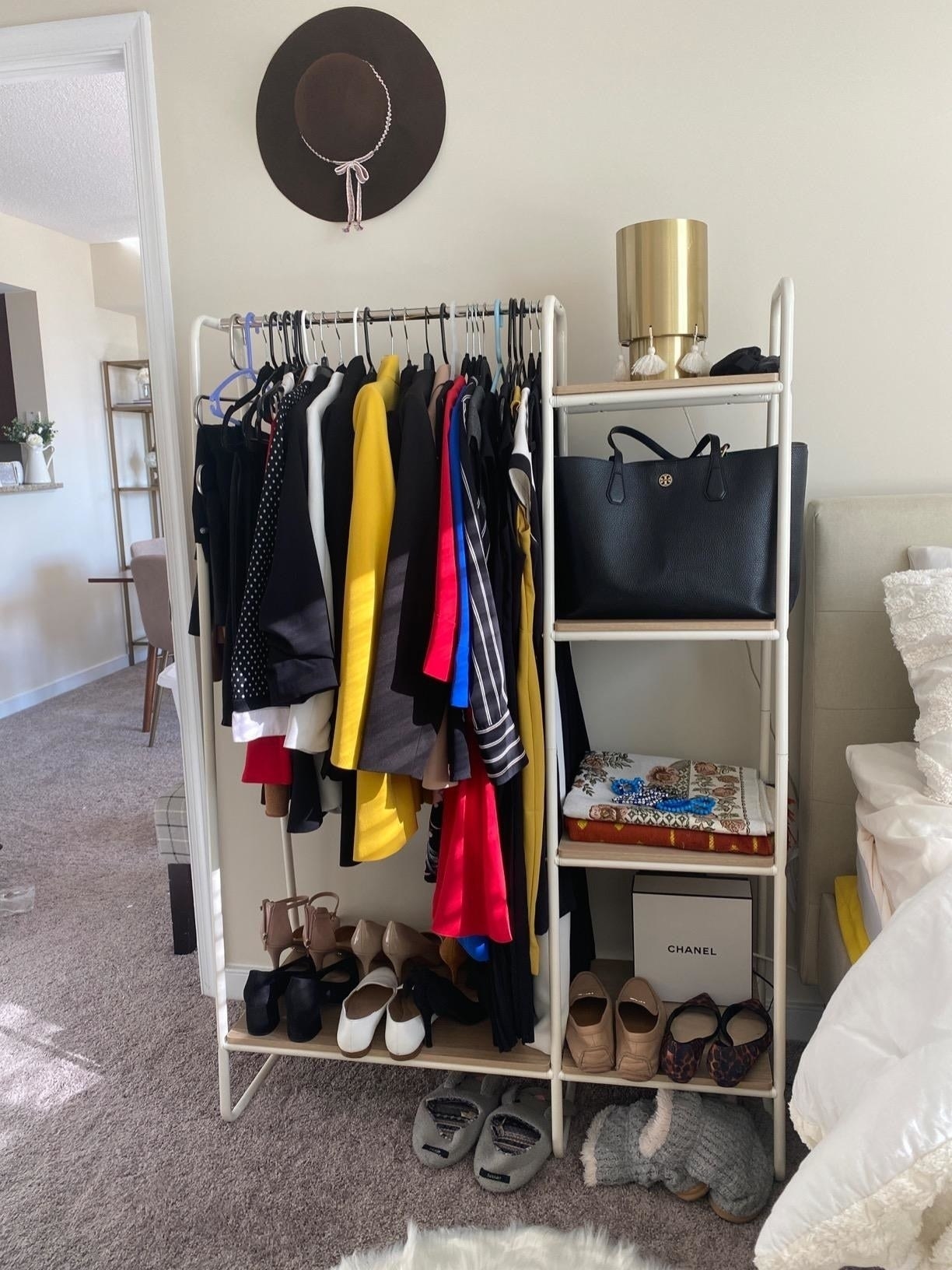 reviewer&#x27;s white garment rack with four shelves storing coats, shoes, and accessories