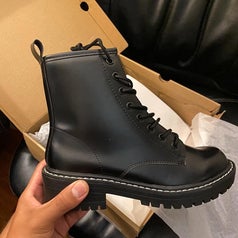 a reviewer holding up the combat boots in black