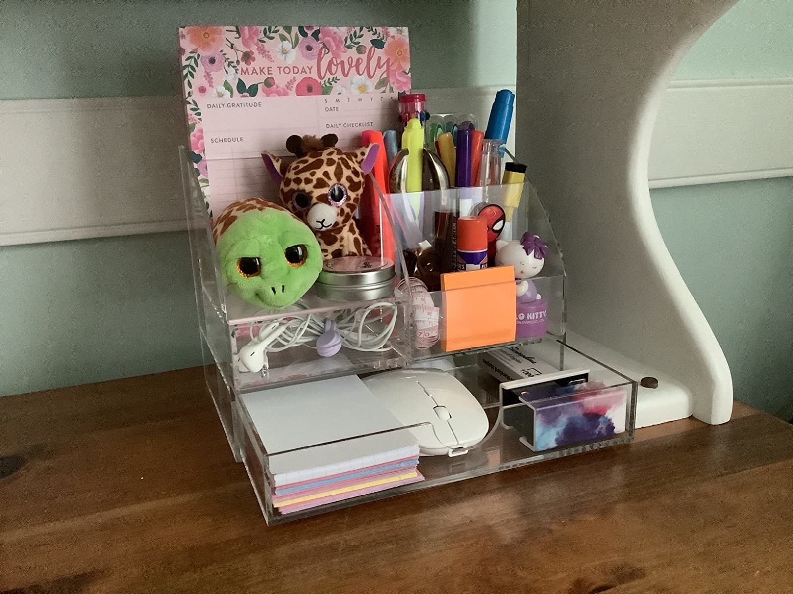 a reviewer photo of the desk organizer with pens paper notebooks and other items organized inside
