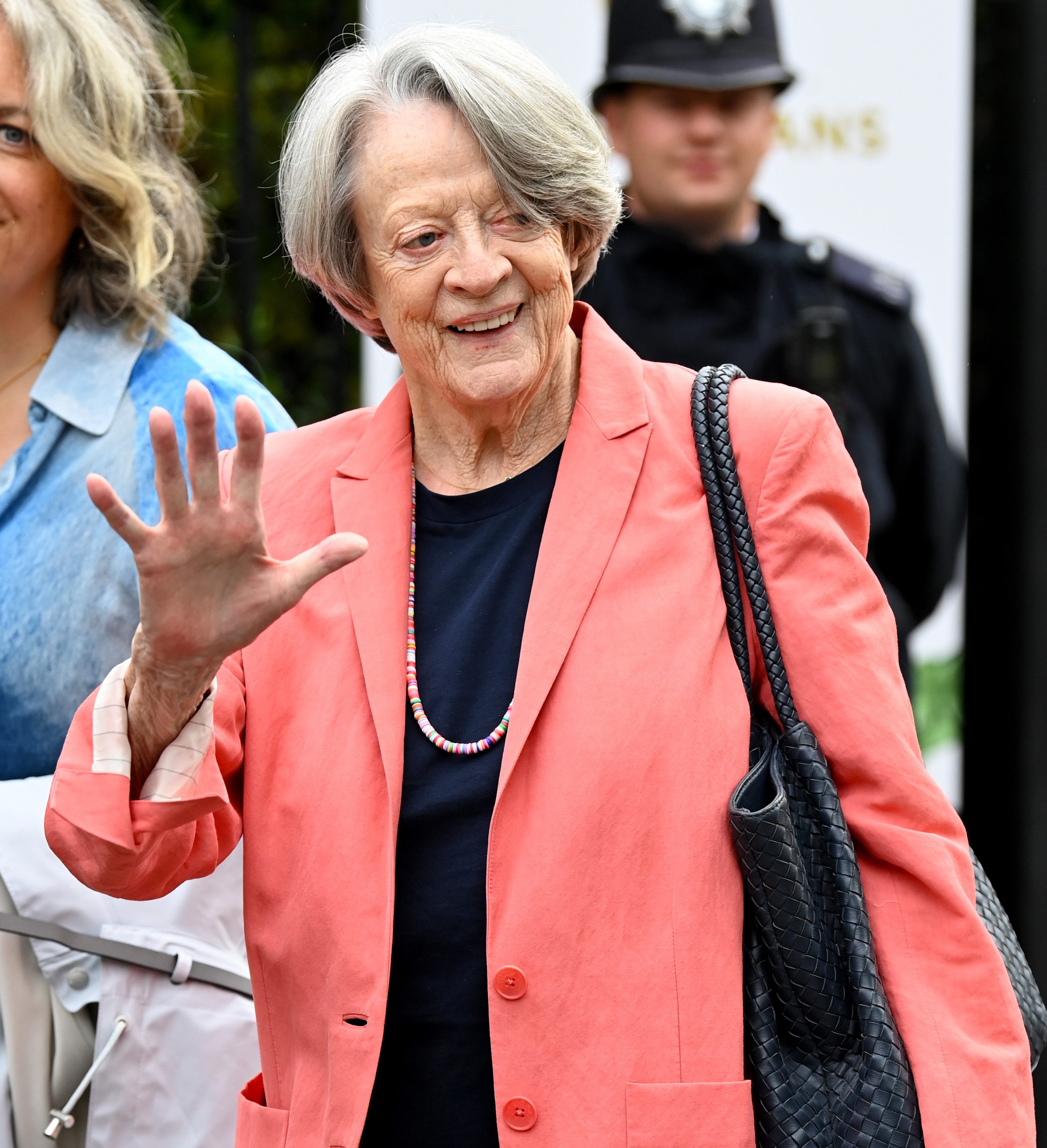 Maggie Smith waving and smiling as she walks