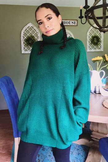 a reviewer wearing the sweater dress in dark green with leggings