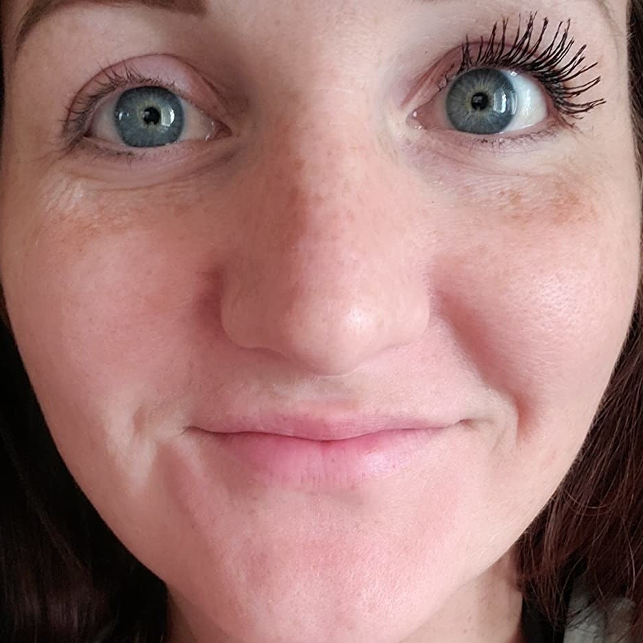 a reviewer with their right eye showing her eyelashes with the mascara which look long and full and fanned out. The lashes on her left eye which don't have the mascara are nearly invisible.