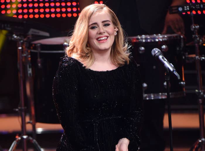 Adele smiles while standing on stage