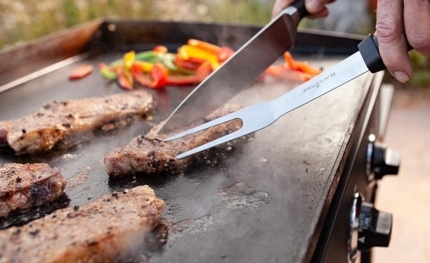 a model cooking steaks on the griddle