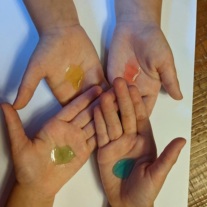 Reviewer's photo showing blue, green, yellow, and red blobs of sanitizer on four hands