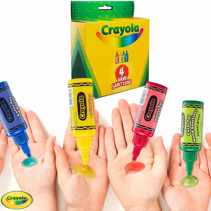 Four hand sanitizer containers shaped like crayons dispensing colorful liquid on hands