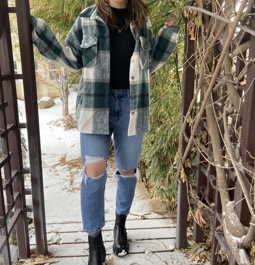 reviewer wearing the shacket in plaid green and white with ripped jeans and black boots