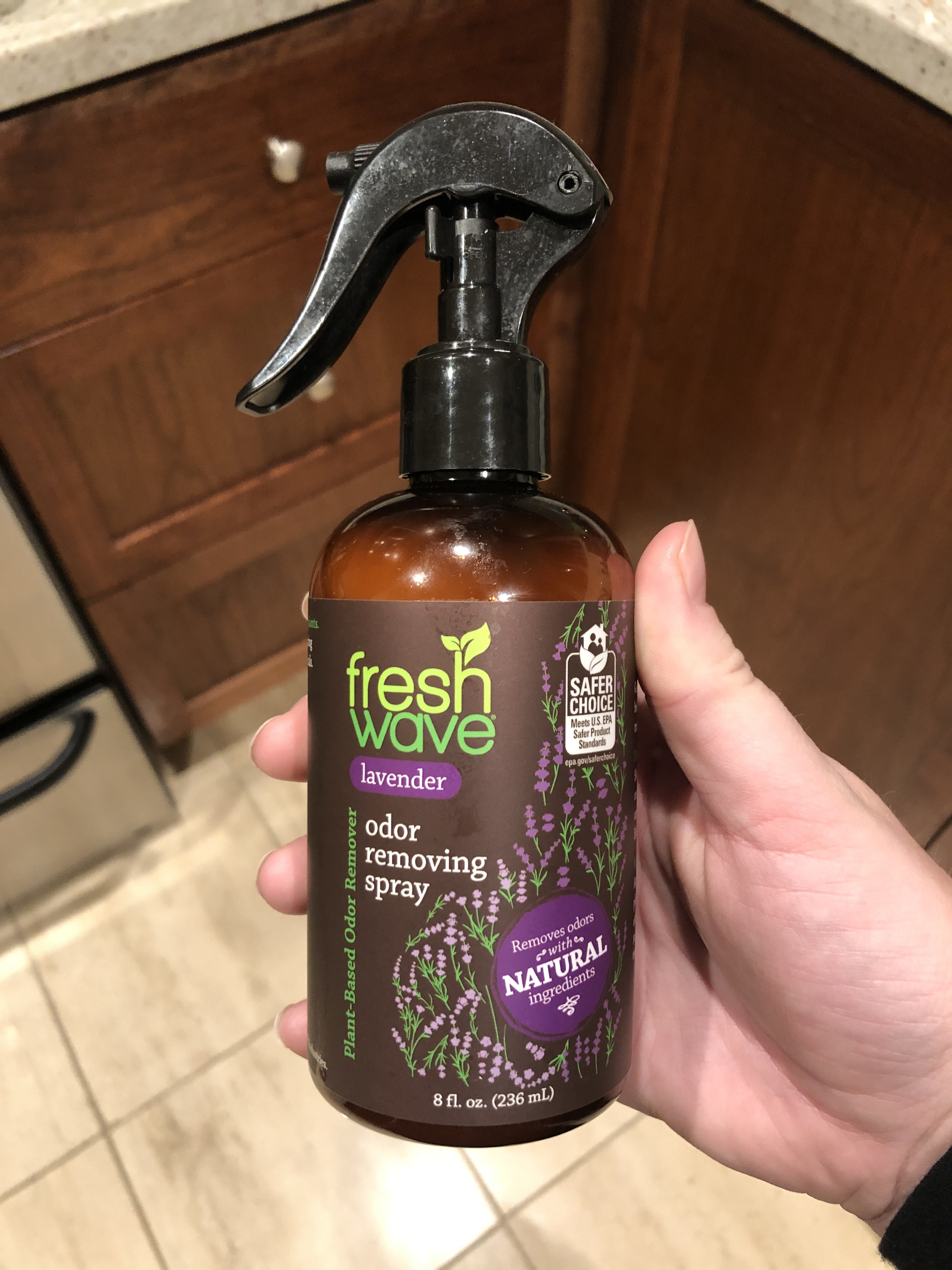 Hand holding a bottle of Fresh Wave natural odor removing spray with lavender essence