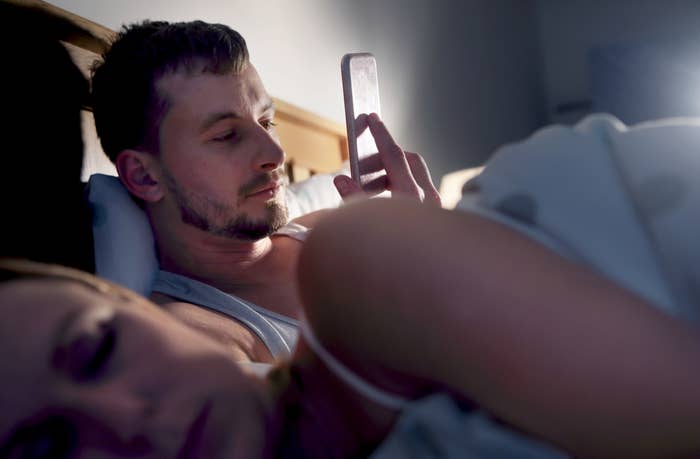 一个男人在妻子睡觉时在床上发短信